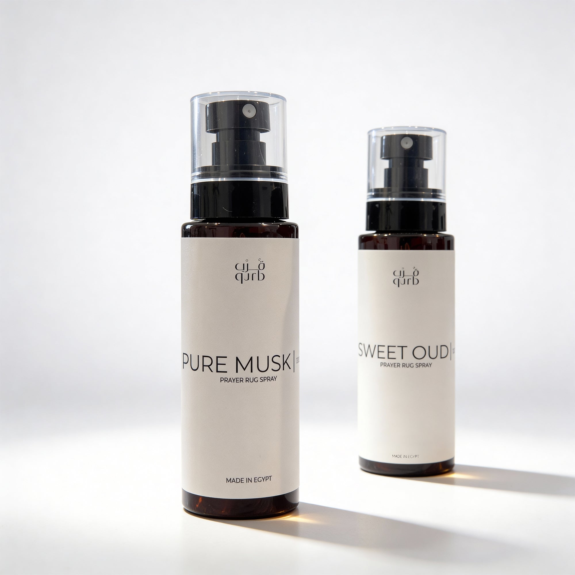 Two bottles of 'Pure Musk' and 'Sweet Oud' by 'al'Qura' on a light background