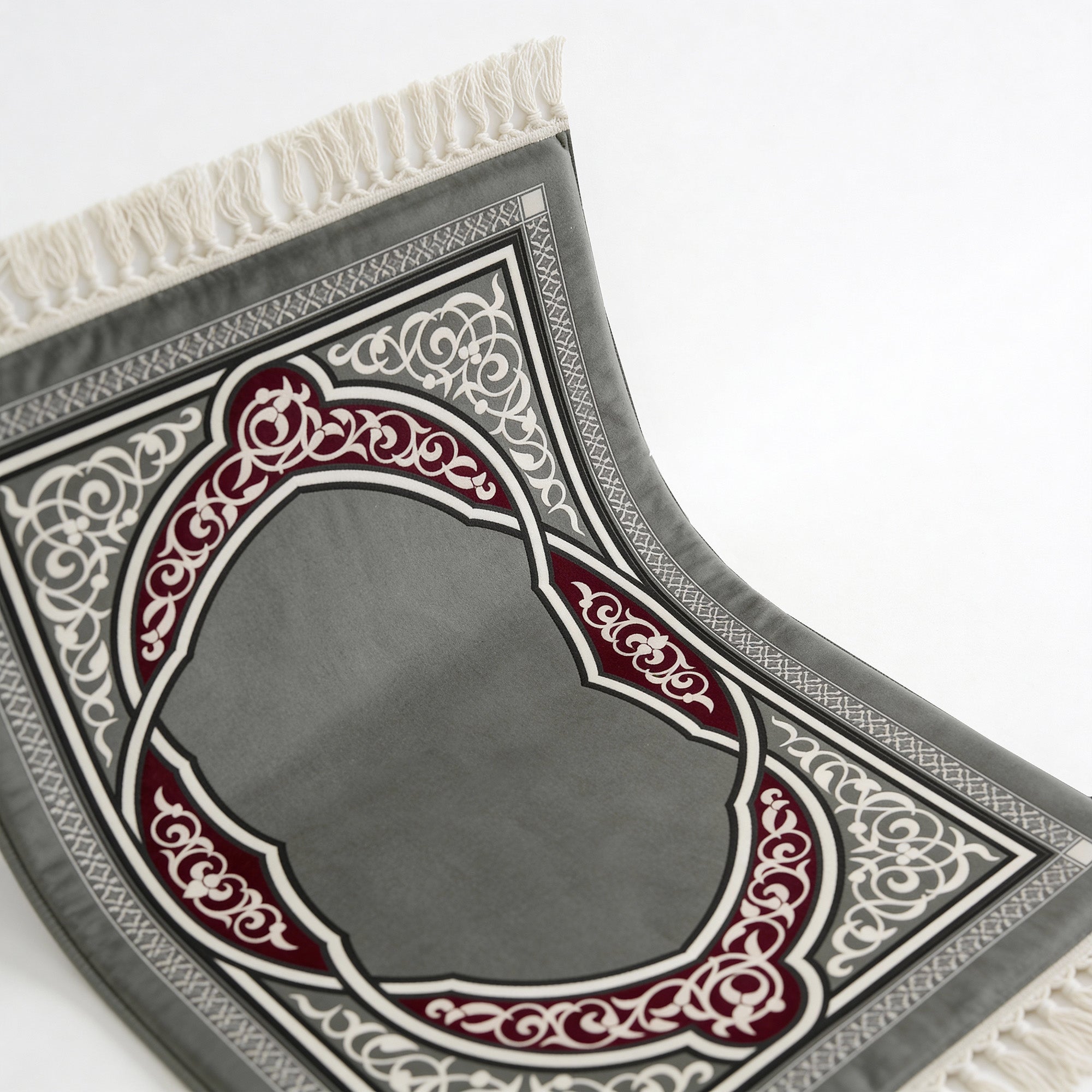 Prayer mat with dark grey base and heart-shaped arch design in red and white trim