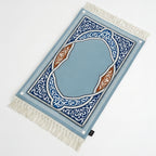 Padded prayer mat with angled view, blue border, and white fringe tassels
