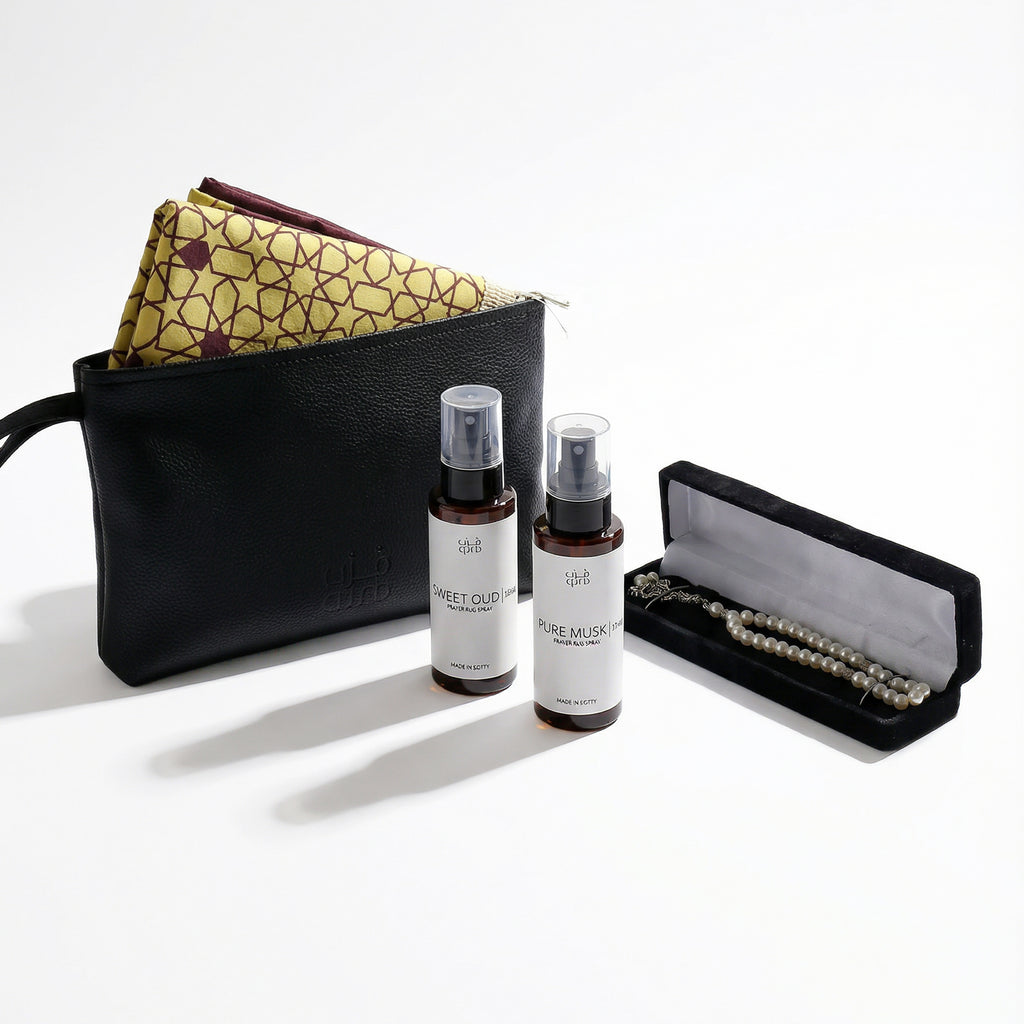 Open gift set with black case, folded patterned fabric, white prayer beads, and two spray bottles
