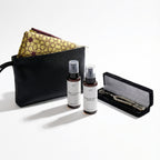 Open gift set with black case, folded patterned fabric, white prayer beads, and two spray bottles