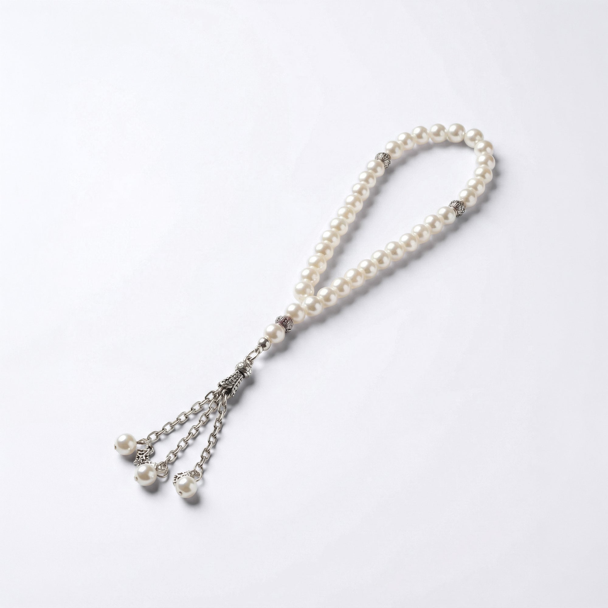 White pearl beaded prayer bracelet with silver-tone charms and tassel-like ends