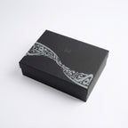 Black gift box with white decorative calligraphy band on the lid