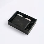 Black leather-style organizer box with rolled spray bottles and beaded bracelet