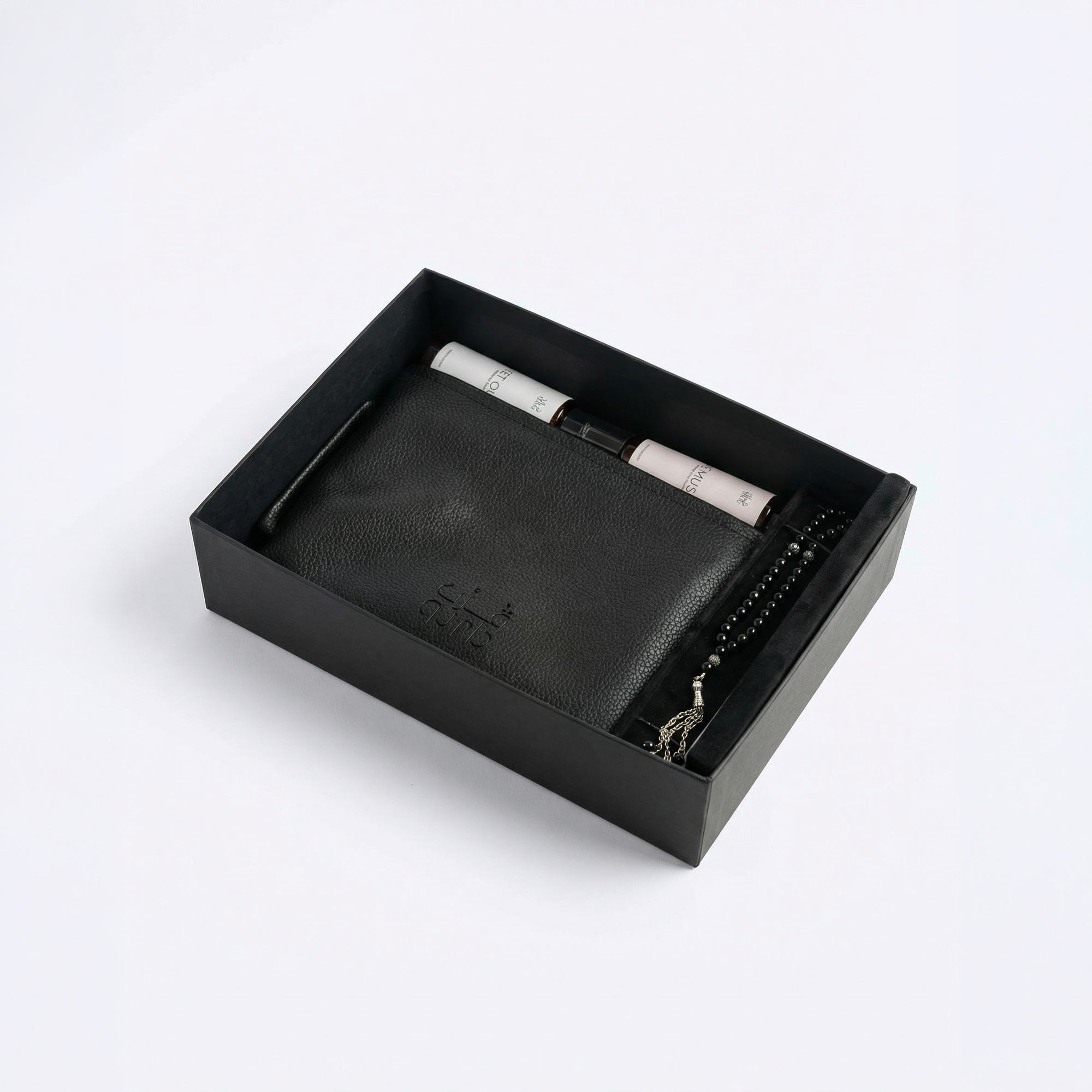 Black leather-style organizer box with rolled spray bottles and beaded bracelet