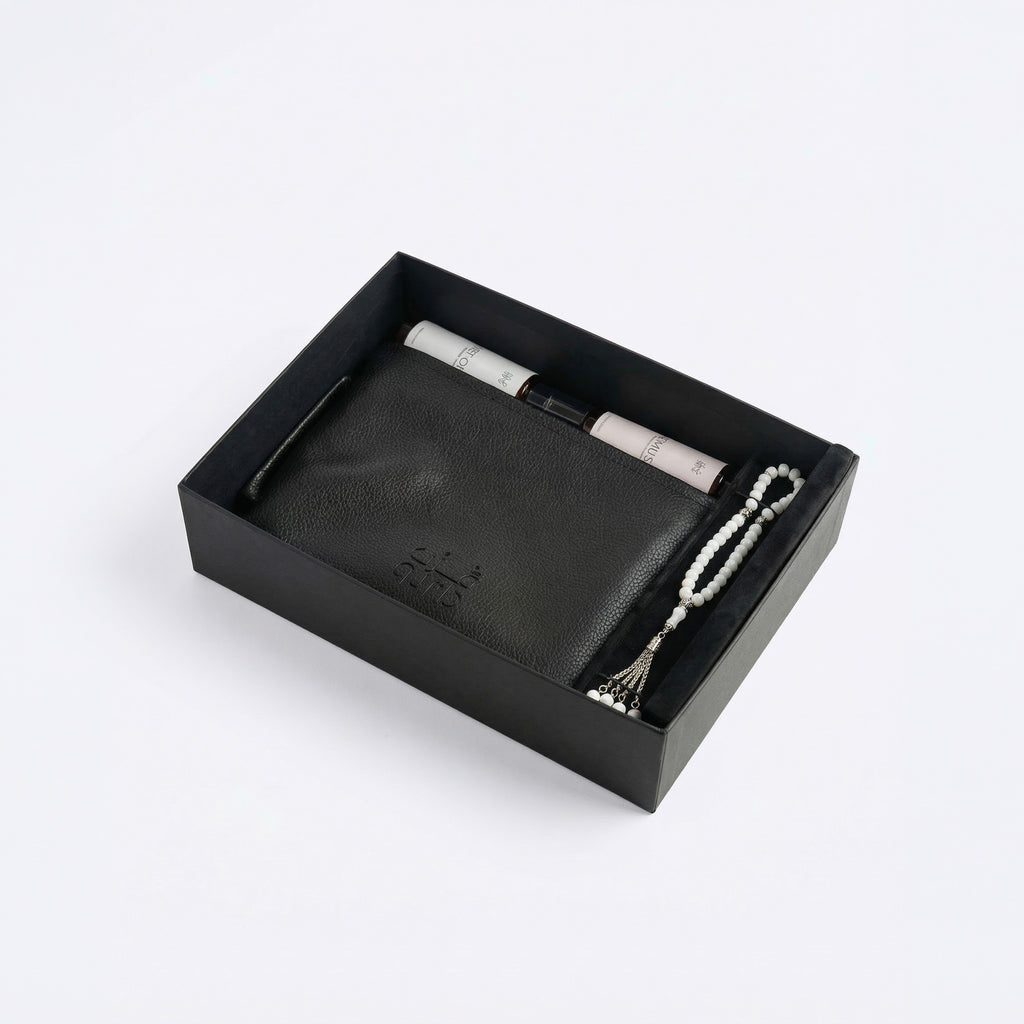 Open black gift box insert with white prayer beads and a small spray bottle